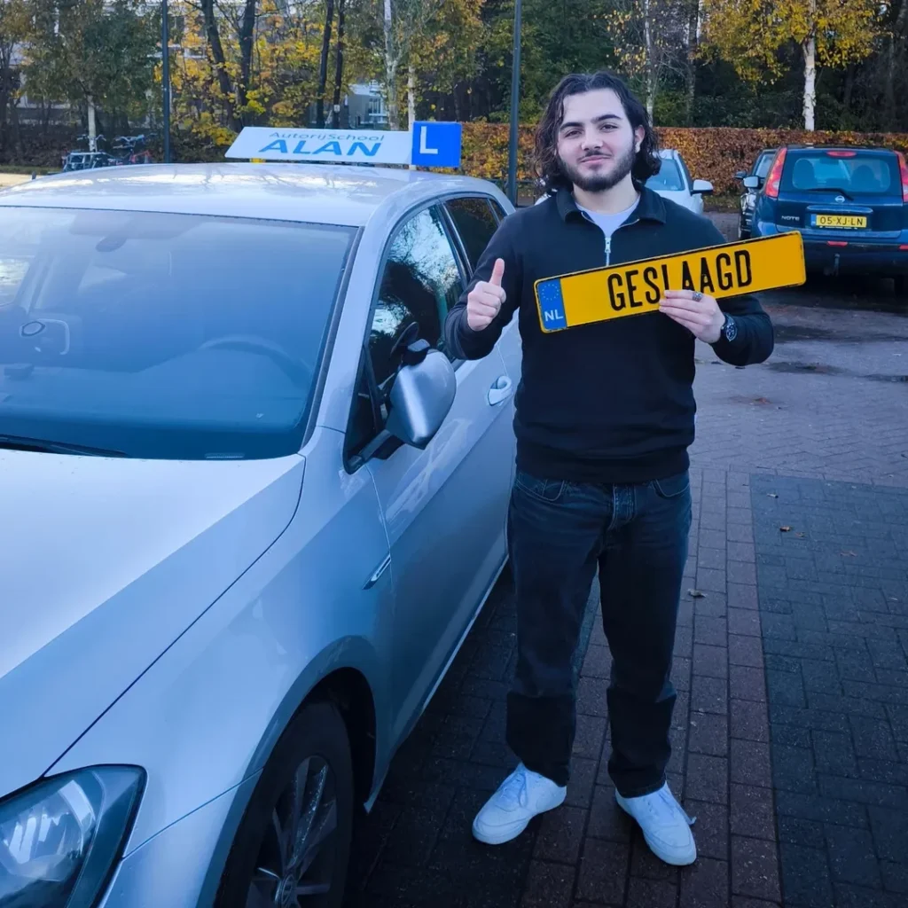 Geslaagde leerling Yassir toont trots zijn rijbewijs bij witte lesauto van Autorijschool ALAN na rijexamen Geslaagde leerling Yassir toont trots zijn rijbewijs bij witte lesauto van Autorijschool ALAN na rijexamen