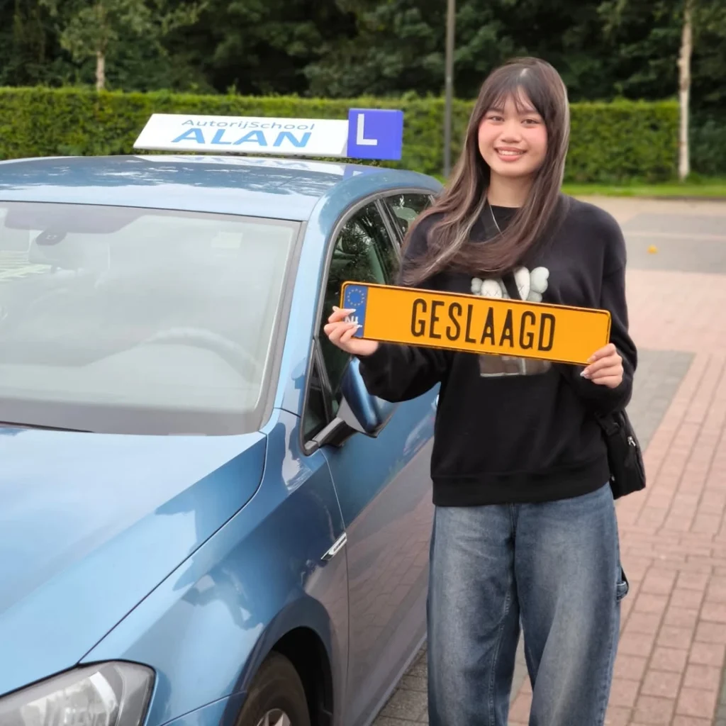 Thi Du toont trots GESLAAGD bord na het behalen van haar rijbewijs bij Autorijschool ALAN naast lesauto Thi Du toont trots GESLAAGD bord na het behalen van haar rijbewijs bij Autorijschool ALAN naast lesauto